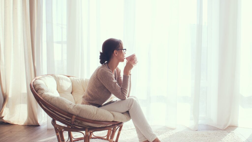 Woman sitting down drinking a hot drink looking calm - representing the serenity and peace achieved through the 333 Calming Rule for anxiety relief